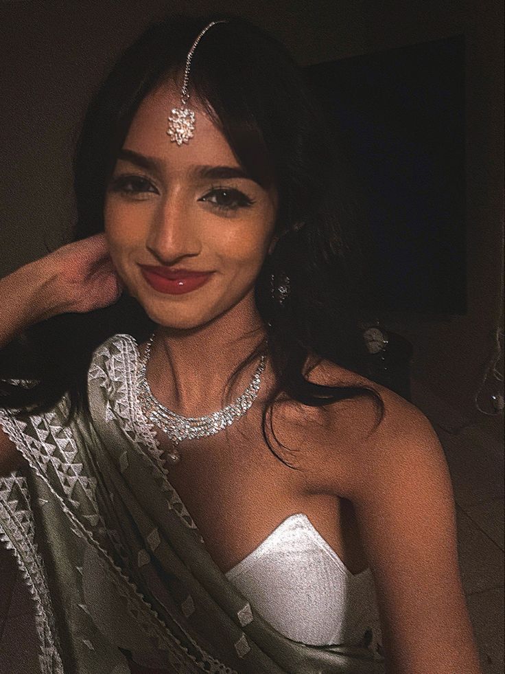 This may contain: a woman in a white dress posing for the camera with her hand on her head