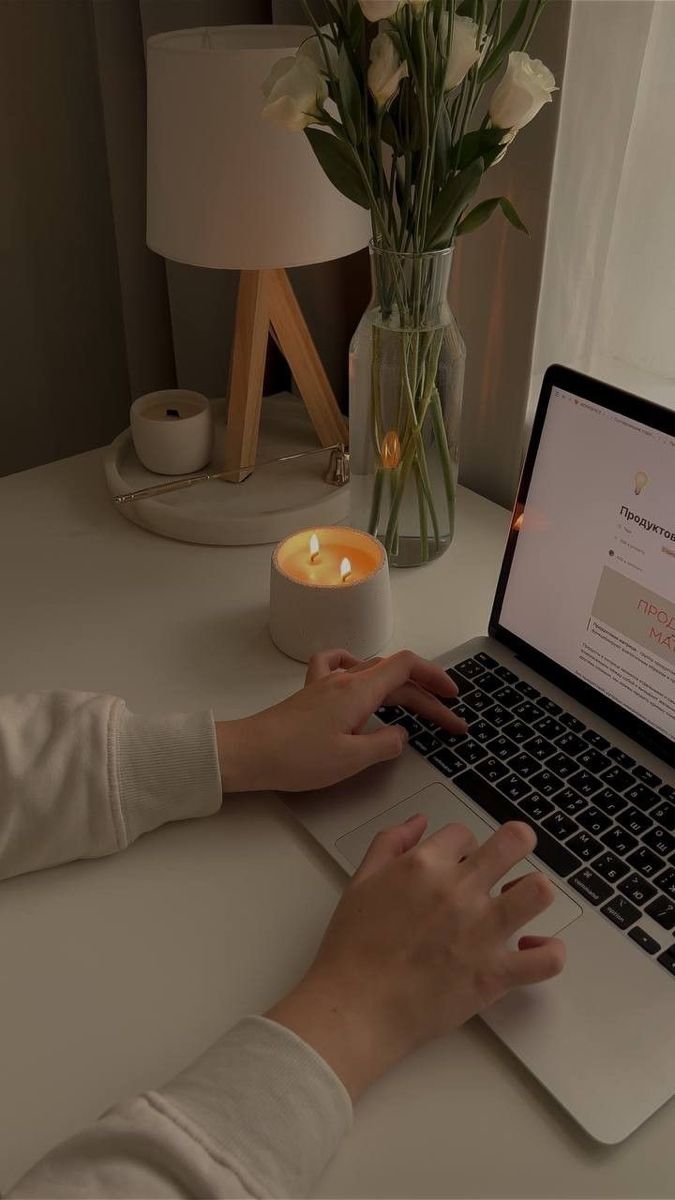 This may contain: a woman is typing on her laptop at the table with flowers in front of her