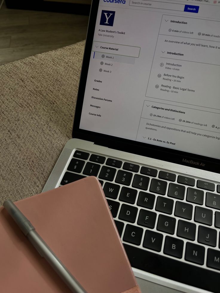This may contain: an open laptop computer sitting on top of a desk next to a notepad and pen