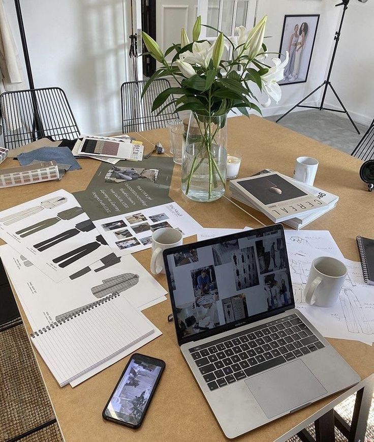 This may contain: an open laptop computer sitting on top of a wooden table next to a vase filled with flowers