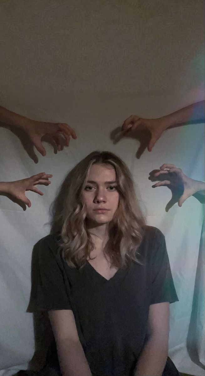 This contains: Girl looking at camera with hands reaching towards her. This is a visual and artistic representation of mental health struggles.