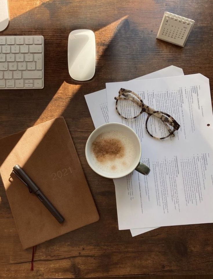 This may contain: a cup of coffee sitting on top of a desk next to a keyboard and mouse