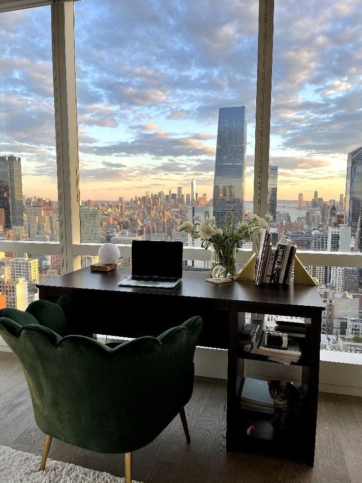 This may contain: a desk with a laptop on it in front of a large window overlooking the city