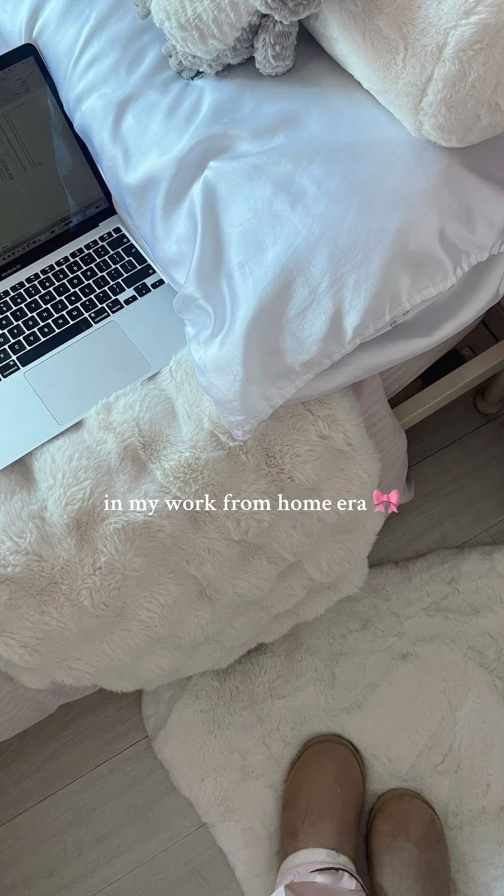 This may contain: a laptop computer sitting on top of a bed next to a pair of slippers