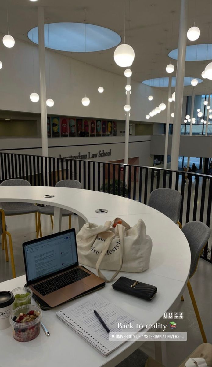 This may contain: a laptop computer sitting on top of a white table next to a bag and pen
