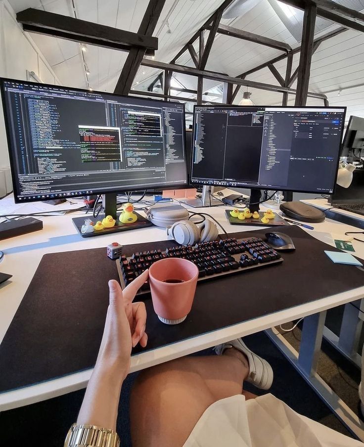 This may contain: a person sitting at a desk with two computer monitors and a keyboard in front of them