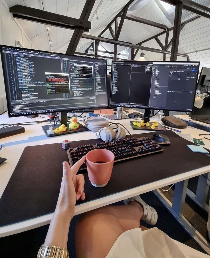 This may contain: a person sitting at a desk with two computer monitors and a keyboard in front of them