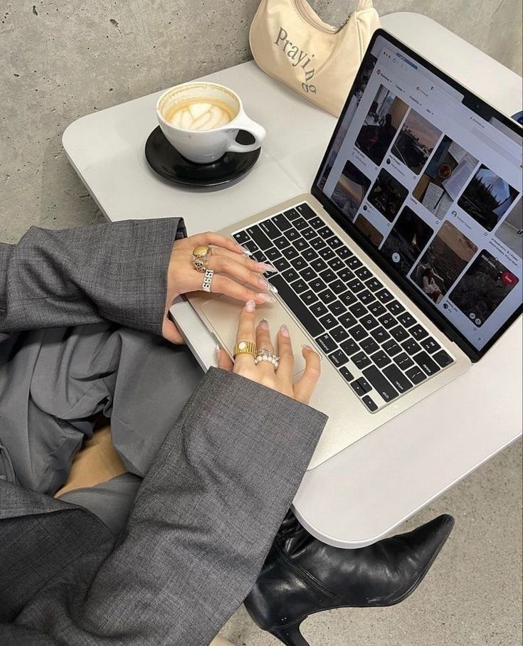 This may contain: a person sitting at a table with a laptop and coffee in front of them on their lap