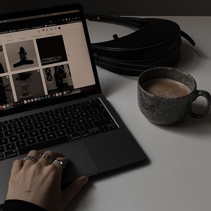 This may contain: a person using a laptop on a desk with a cup of coffee in front of them