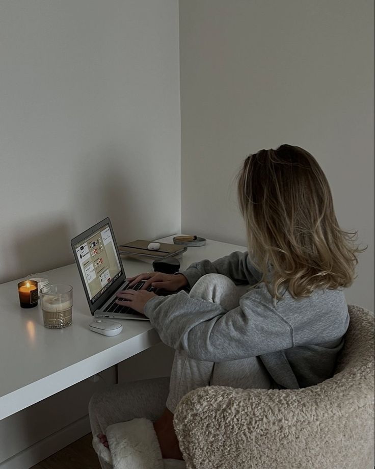 This may contain: a woman sitting at a desk using a laptop computer