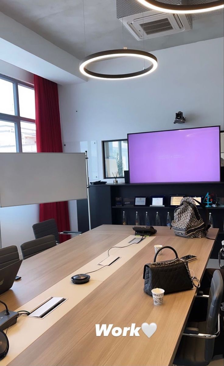 This may contain: an empty conference room with two large screens on the wall
