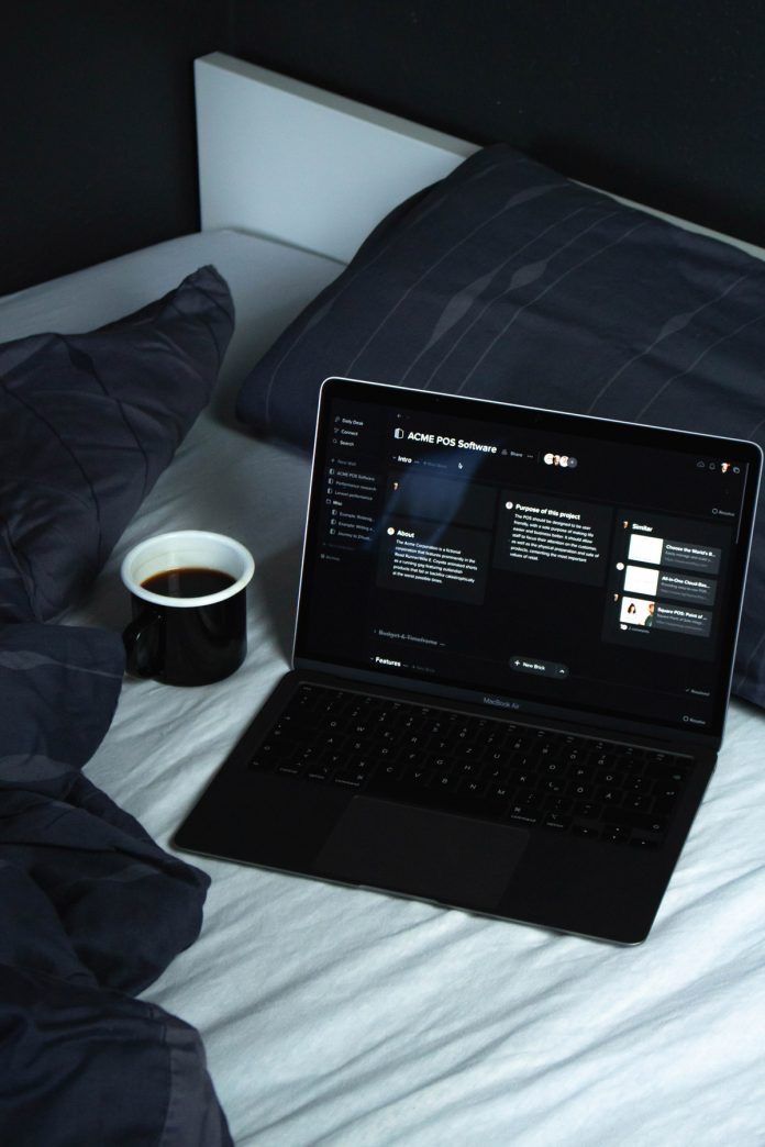 This may contain: an open laptop computer sitting on top of a bed next to a cup of coffee