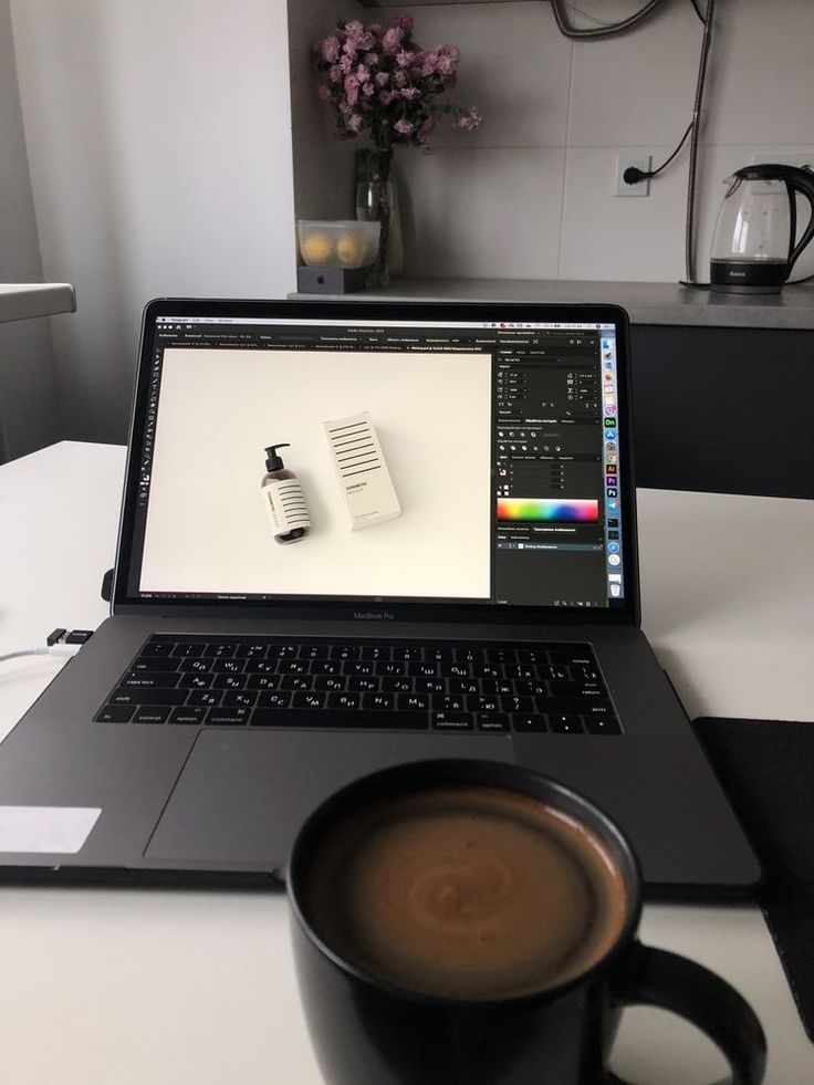 This may contain: an open laptop computer sitting on top of a desk next to a cup of coffee