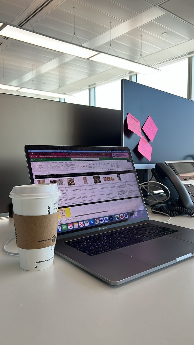 This may contain: an open laptop computer sitting on top of a desk next to a cup of coffee