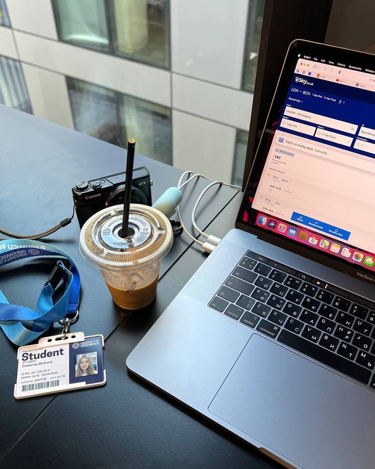 This may contain: an open laptop computer sitting on top of a desk next to a cup of coffee