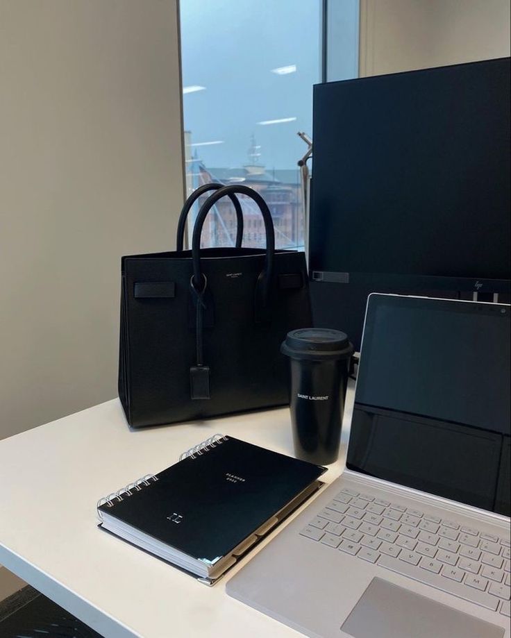 This may contain: an open laptop computer sitting on top of a white desk next to a black bag