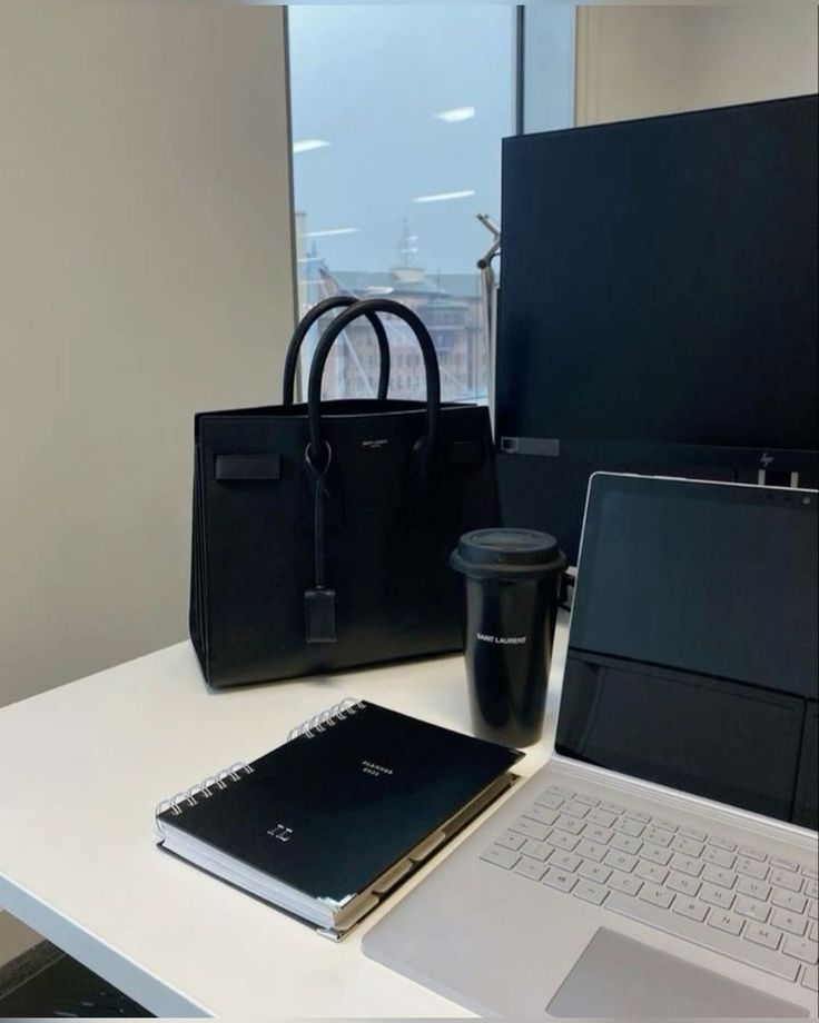 This may contain: an open laptop computer sitting on top of a white desk next to a black bag