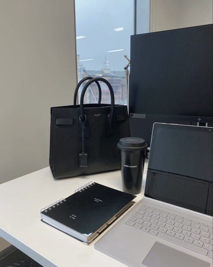 This may contain: an open laptop computer sitting on top of a white desk next to a black bag