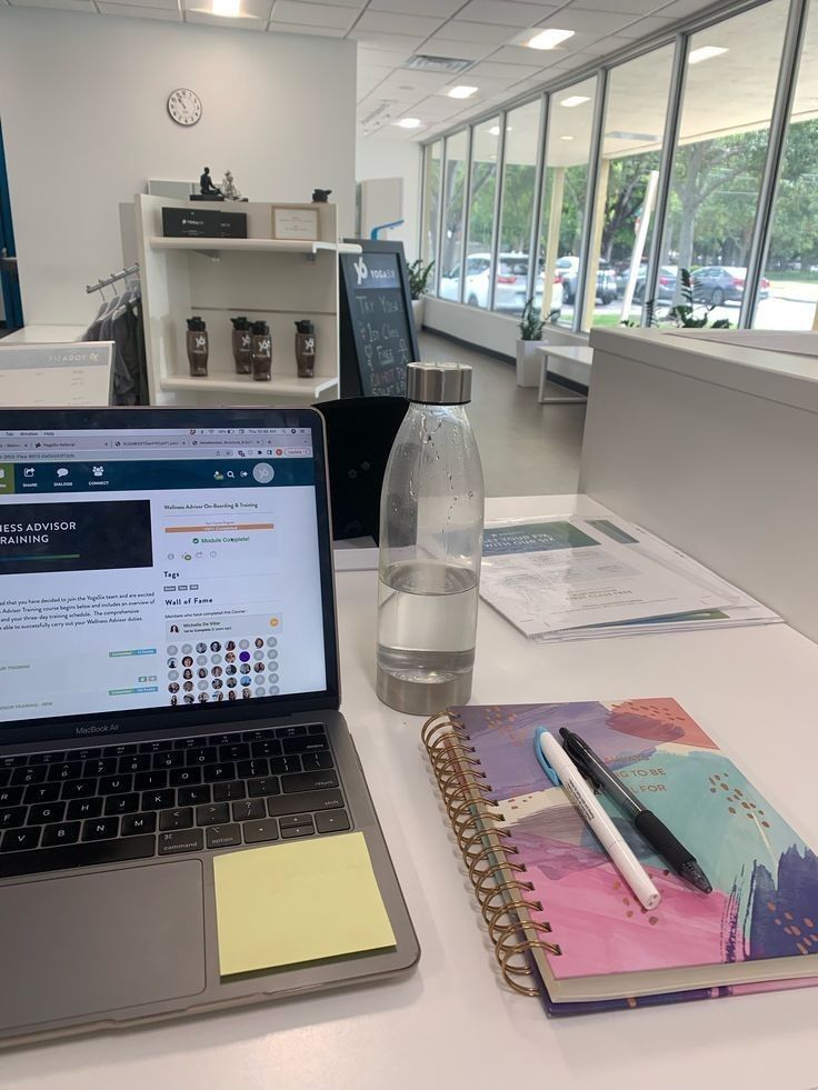 This may contain: an open laptop computer sitting on top of a white desk next to a note pad