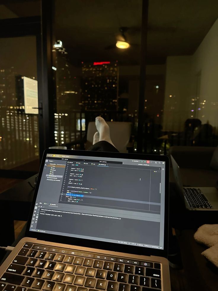 This may contain: an open laptop computer sitting on top of a wooden desk in front of a window