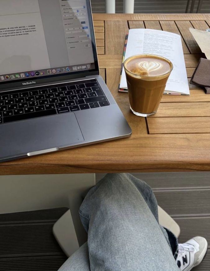 This may contain: an open laptop computer sitting on top of a wooden table next to a cup of coffee
