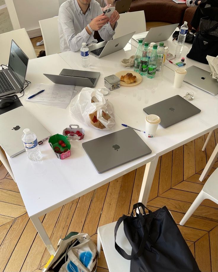This may contain: two people sitting at a table with laptops and food on the table in front of them