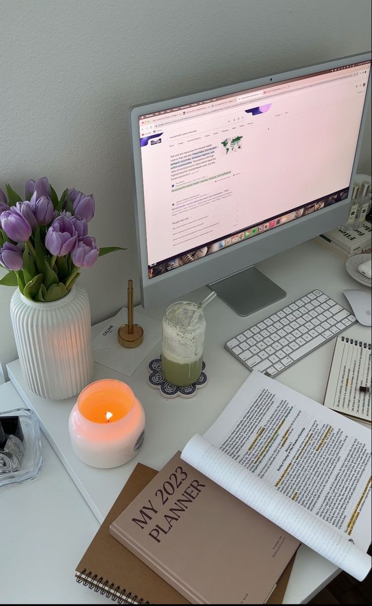 This may contain: a computer monitor sitting on top of a desk next to a keyboard and mouse with a lit candle