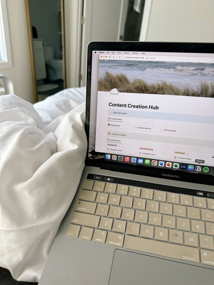 This may contain: a laptop computer sitting on top of a bed next to a white comforter and pillows