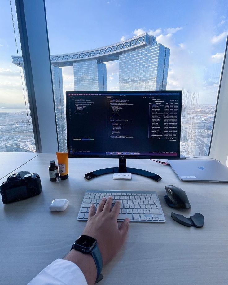 This may contain: a person typing on a keyboard in front of a computer monitor with a view of the city