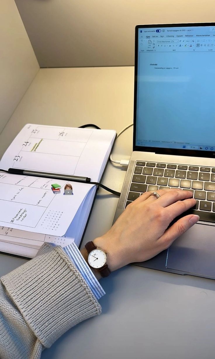 This may contain: a person using a laptop computer on top of a desk next to several binders