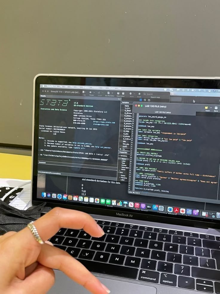 This may contain: a person using a laptop computer with code on the screen and hand pointing at it