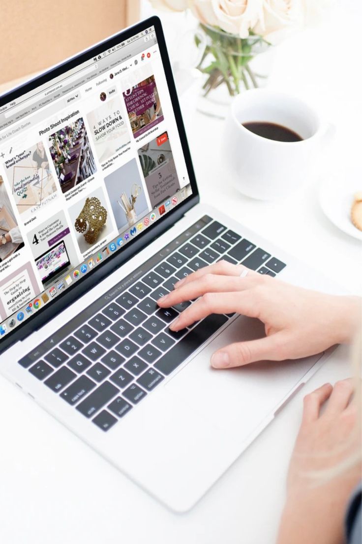 This may contain: a woman is typing on her laptop at a table with coffee and flowers in the background