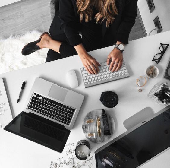 This may contain: a woman sitting at a desk using a laptop computer with her hands on the keyboard