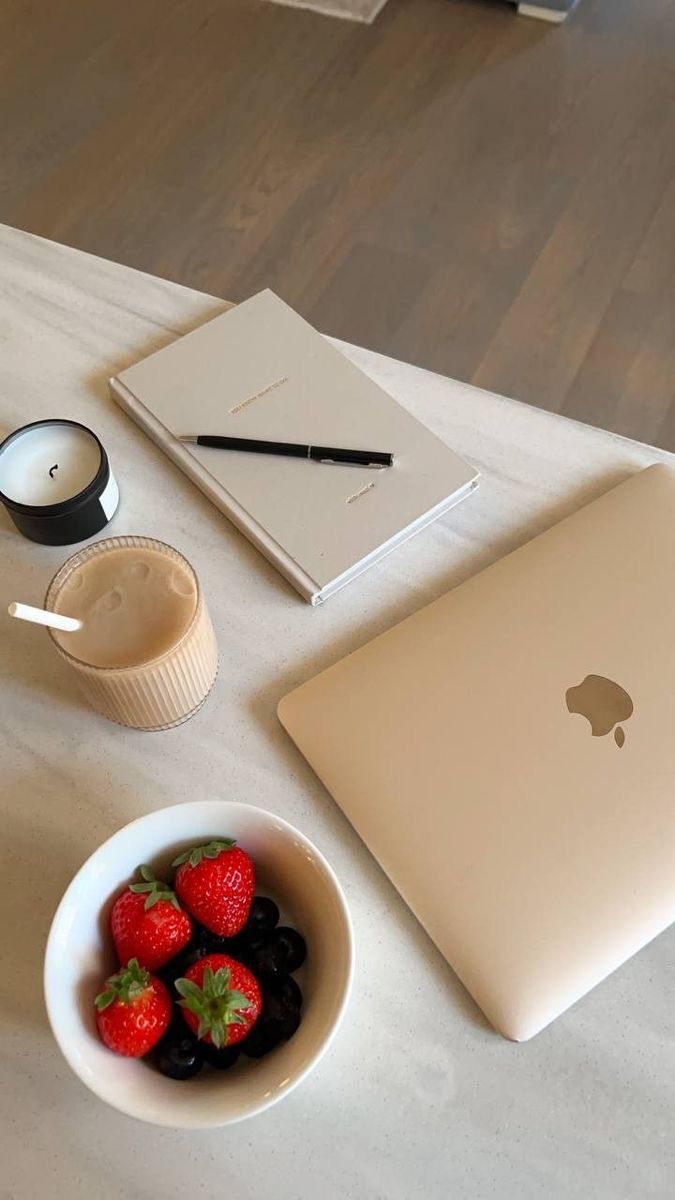 This may contain: an apple laptop and strawberries in a bowl on a table