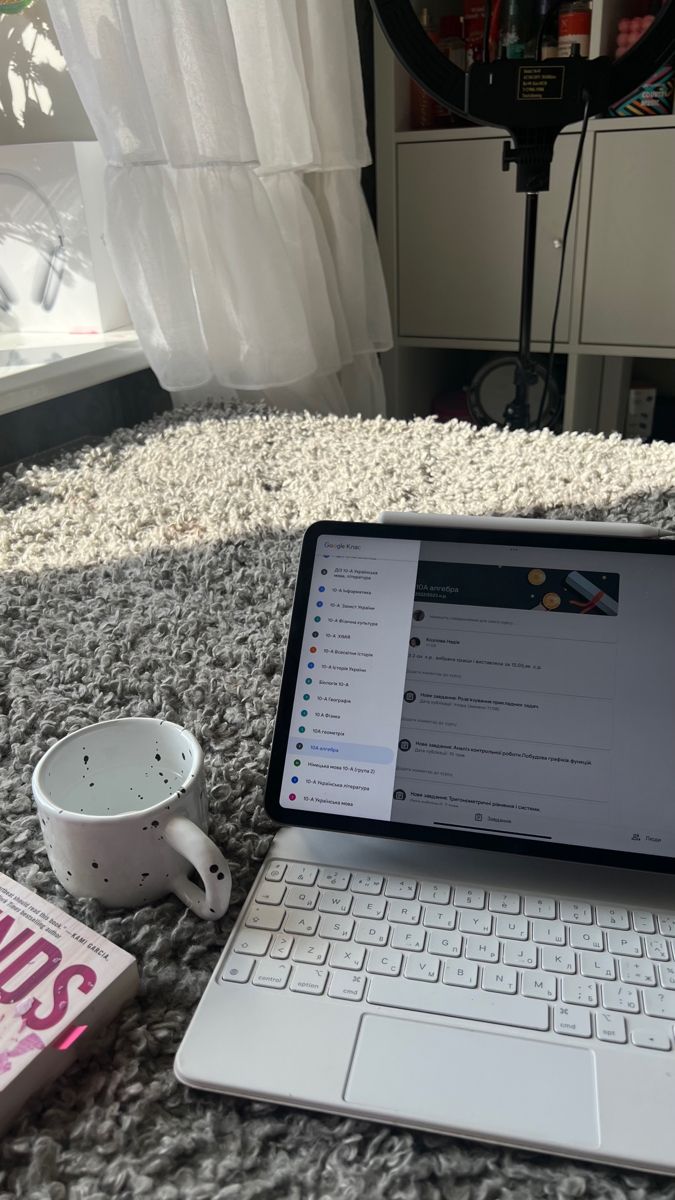 This may contain: an open laptop computer sitting on top of a bed next to a cup and saucer