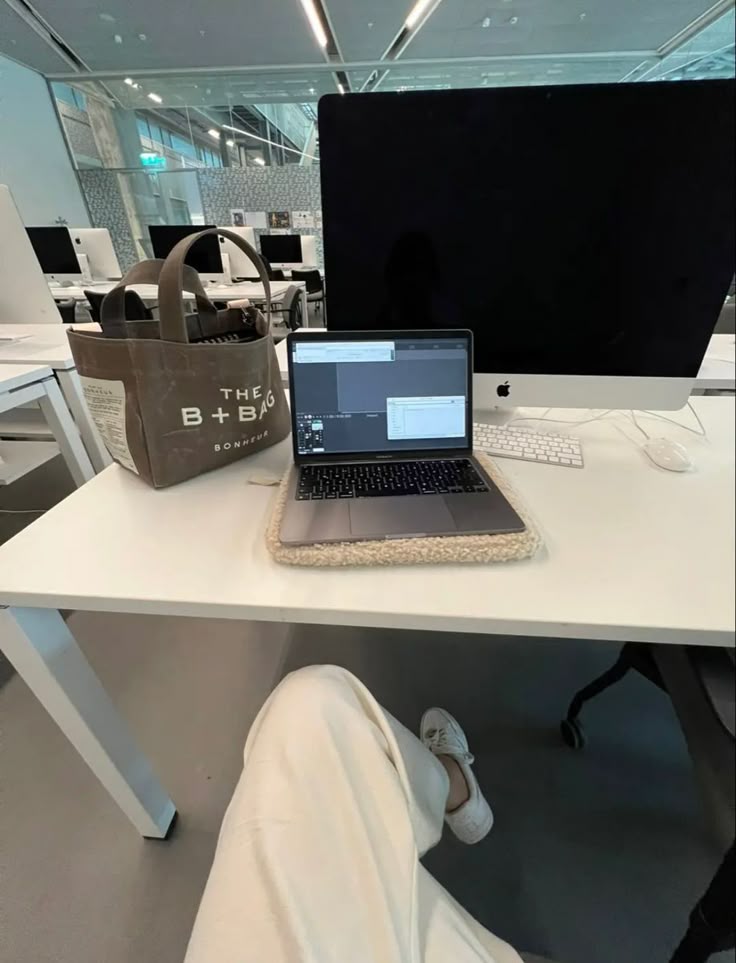 This may contain: an open laptop computer sitting on top of a white desk next to a brown bag