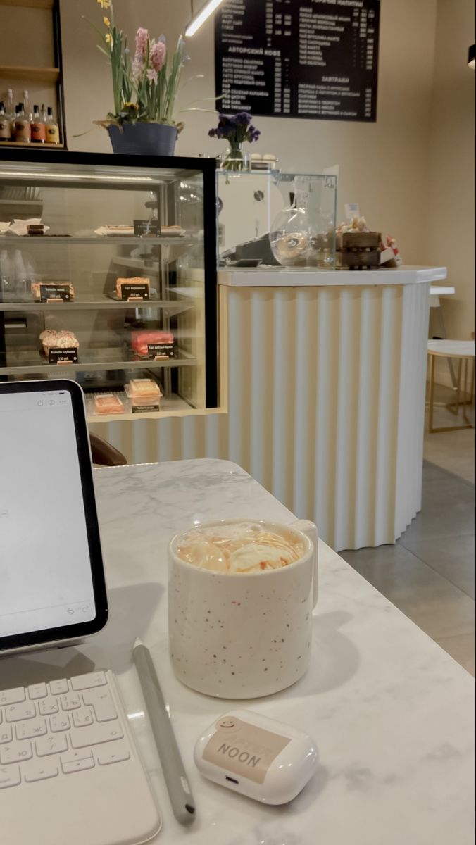 This may contain: an open laptop computer sitting on top of a white table next to a cup of coffee