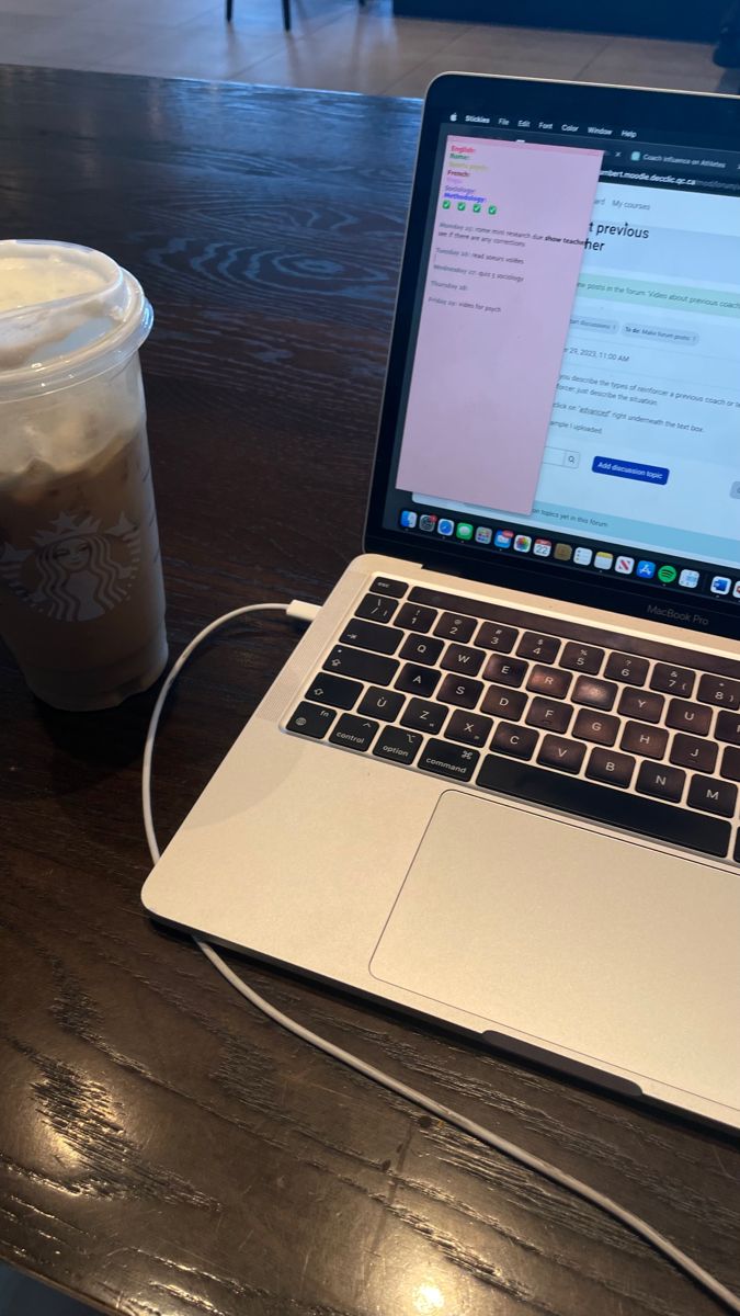 This may contain: an open laptop computer sitting on top of a wooden table next to a cup of coffee