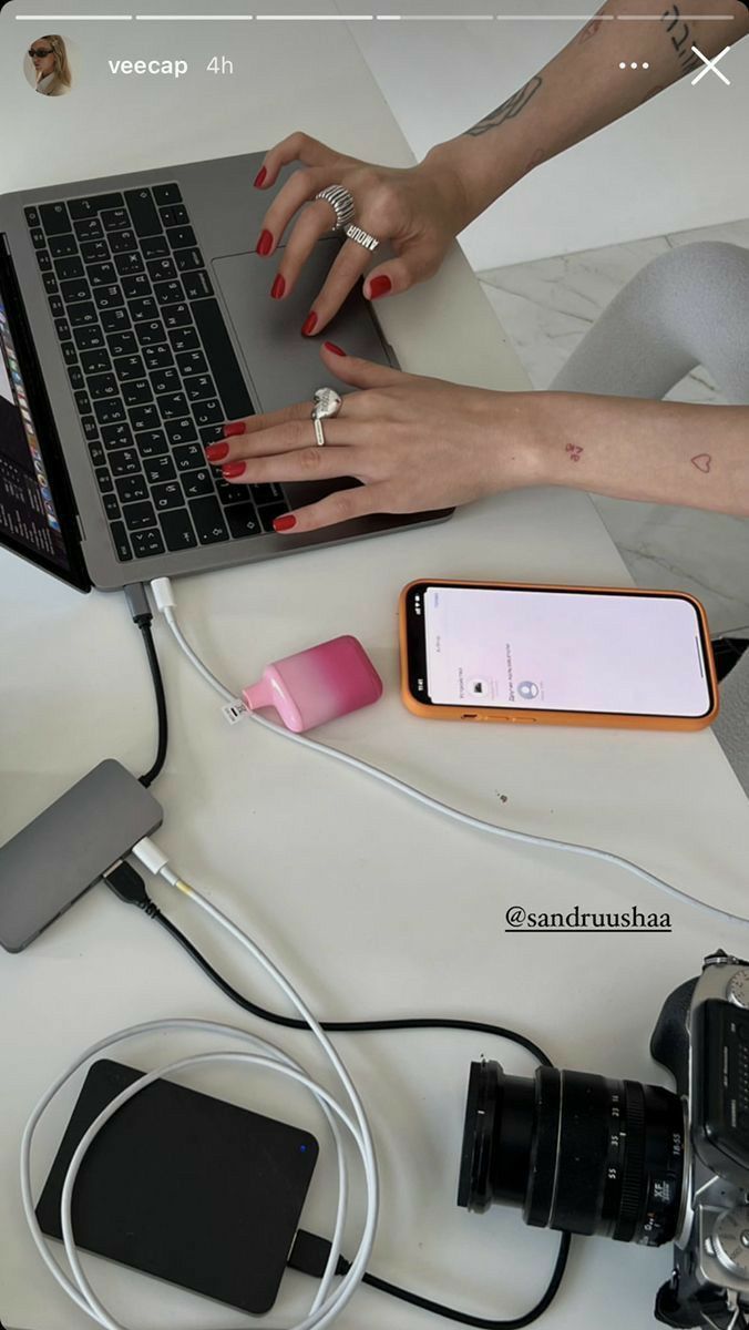 This may contain: the woman is working on her laptop while she's surrounded by other electronics and gadgets